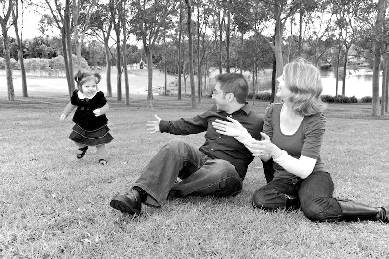 B&W little girl running away from parents open arms - family portrait photography sydney